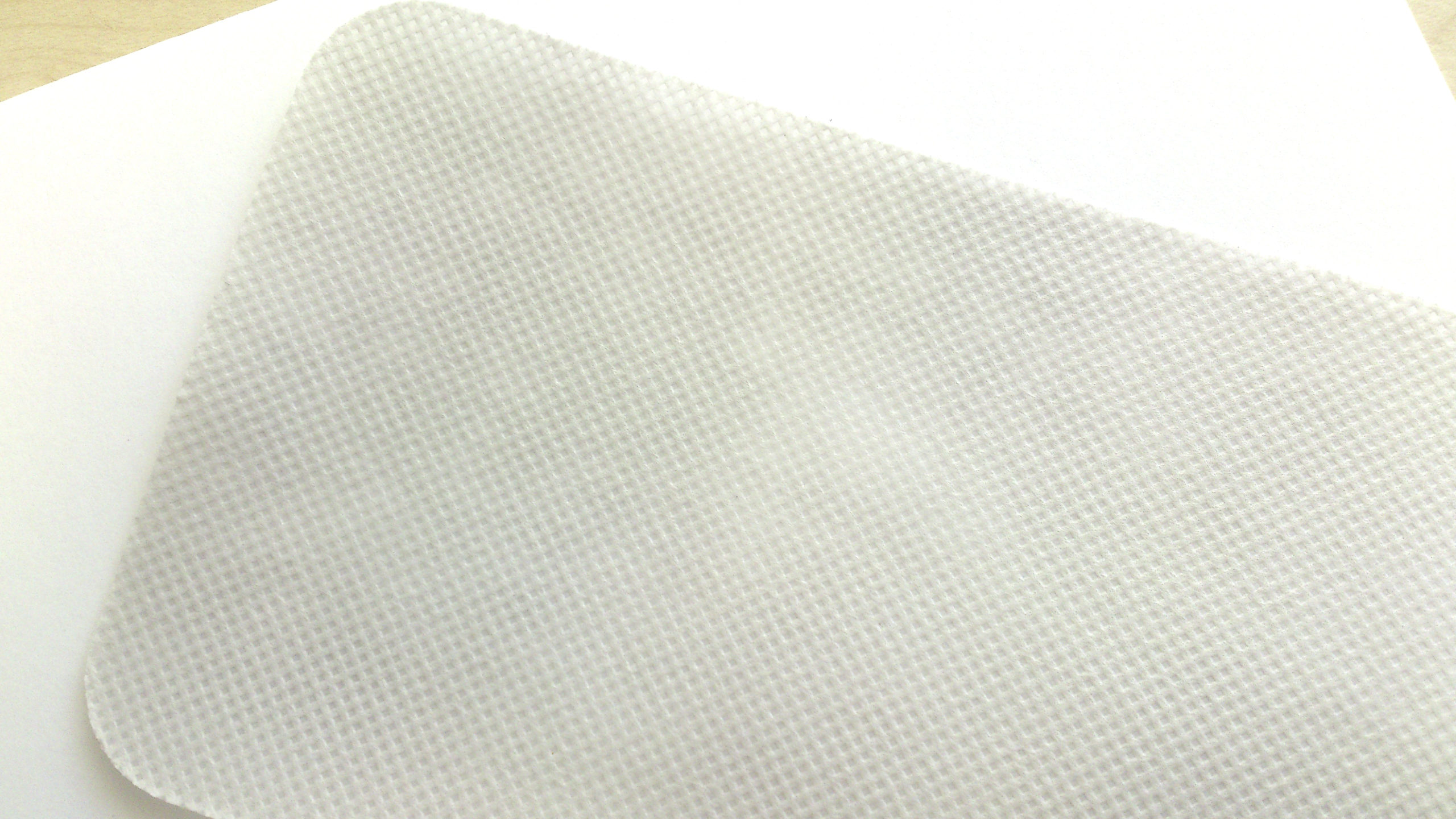 A close-up view of the Zerøtex disposable curtain, featuring a white textured surface with rounded corners, placed on a light background.