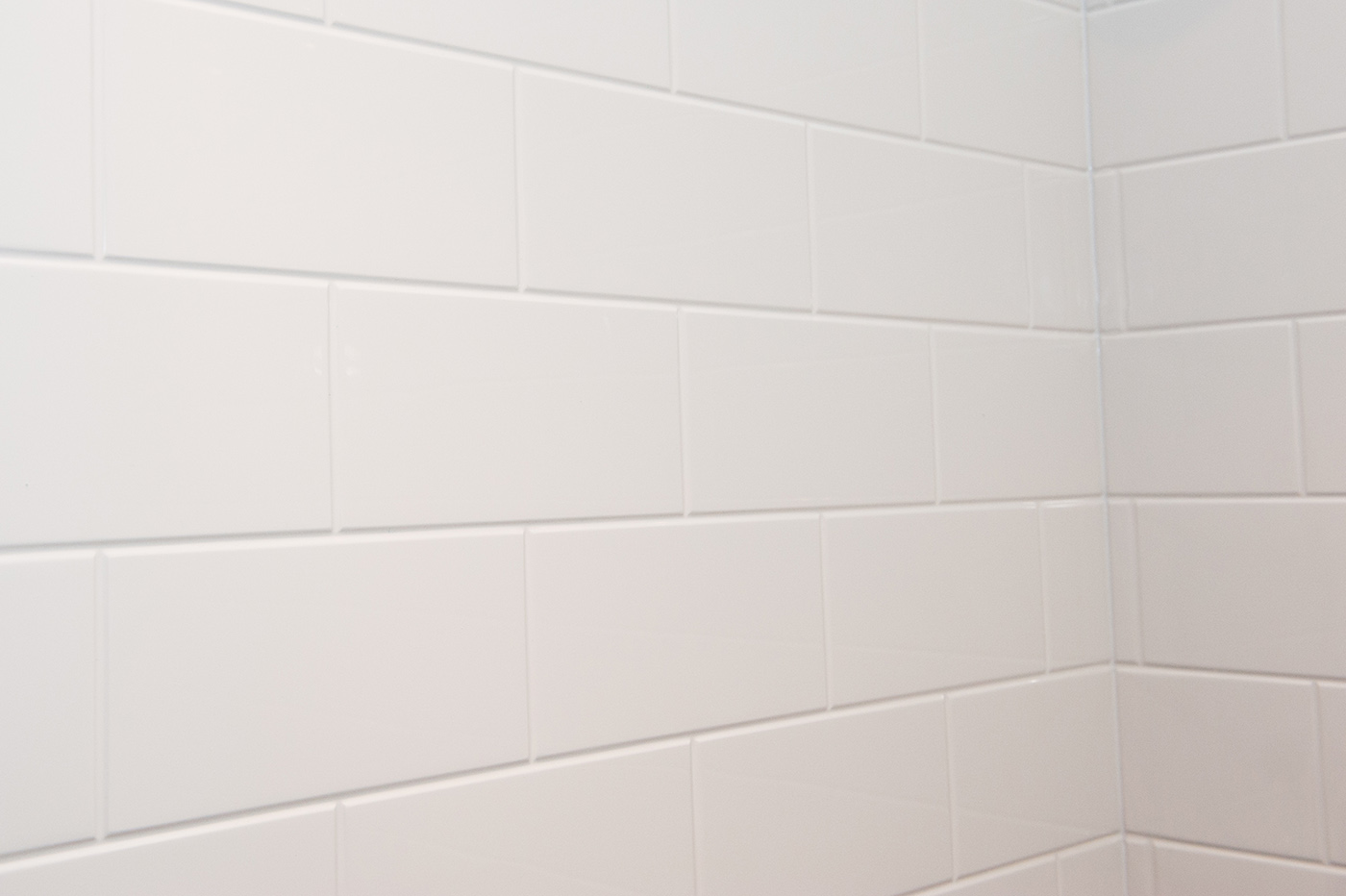 The 5LBS6030.V2 L/R Five Piece 60” x 30” Curbed Shower features a “Subway Tile” design with smooth white rectangular tiles in a running bond pattern, neat grout lines, and a clean finish formed at the corner.